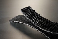 Conveyor belt folded in half to show the black rough top pvc cover and the black fabric bottom