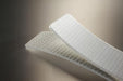 Conveyor belt folded in half to show the white pvc cover and the white fabric bottom